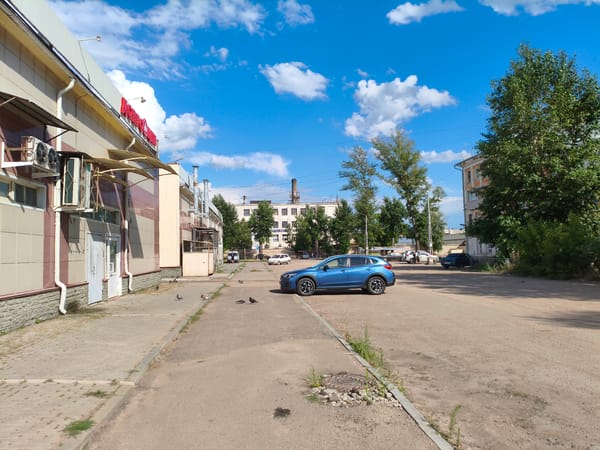 Older apartment complex, parked cars, and a vending machine mid-pour
