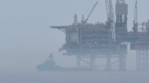 Red vessel operates near oil platform in foggy conditions