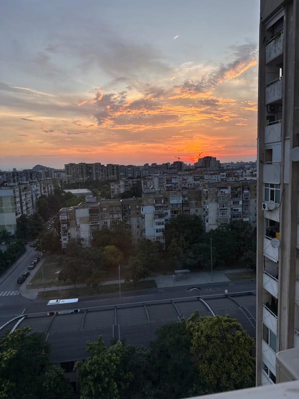 Sunset over the city while a soccer match plays indoors