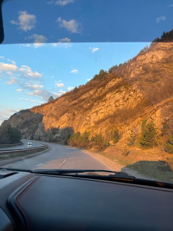 Vehicle travels past steep rock formation in Pernik, Bulgaria