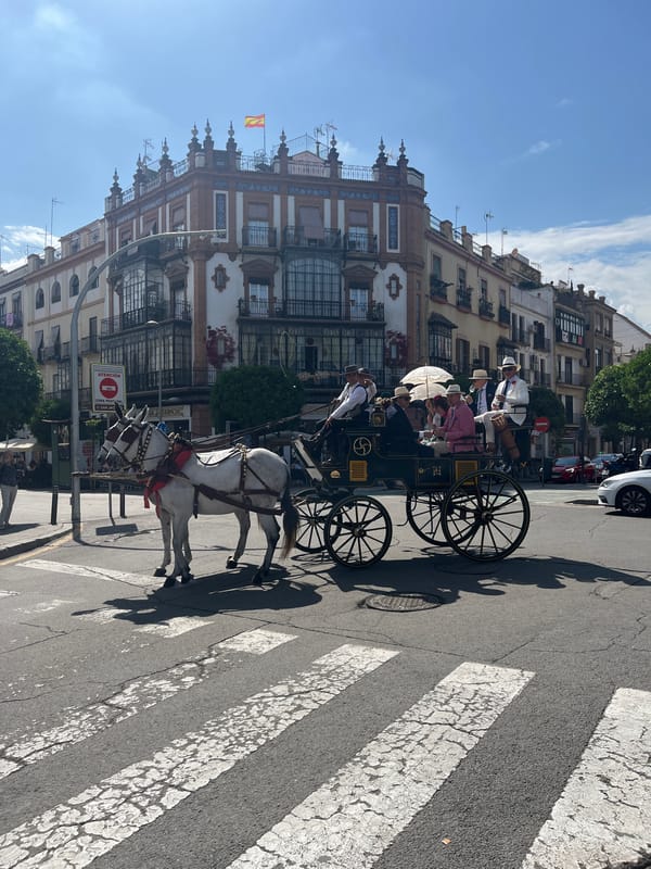 Horse carriage crosses pedestrian walkway in busy Seville square