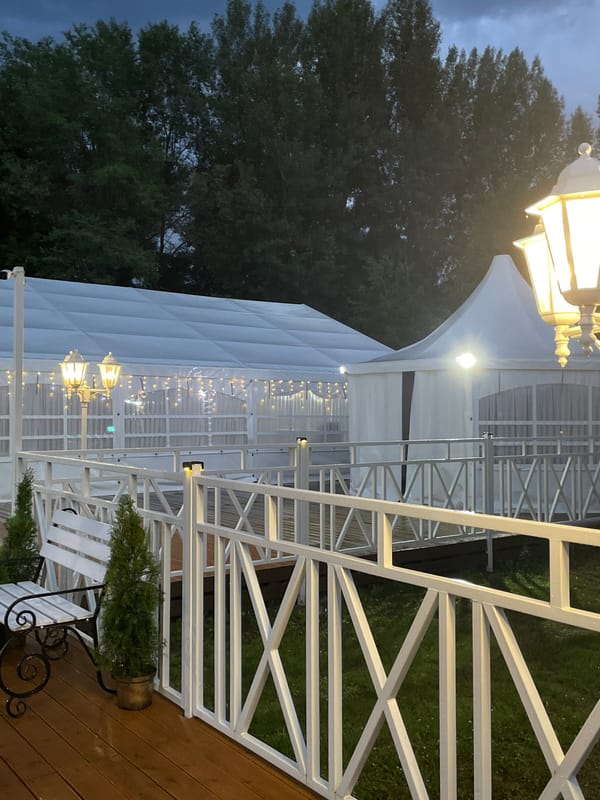 Outdoor wedding venue ready with floral arch and white tents