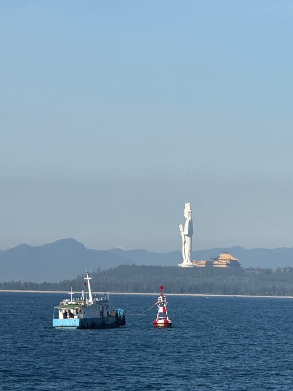 Fishing boats and a striped lighthouse off the central Vietnamese coast