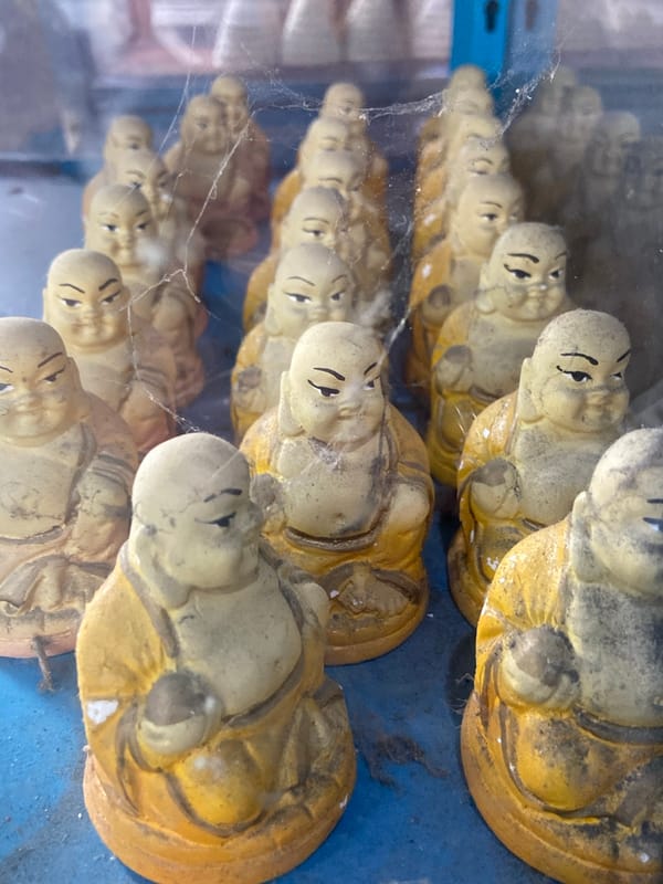 Aged Buddha figurines displayed behind glass in Venezuelan town