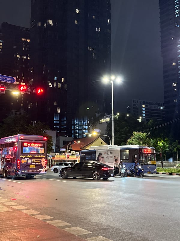Wet Bangkok streets at night, live music inside a World Cup bar