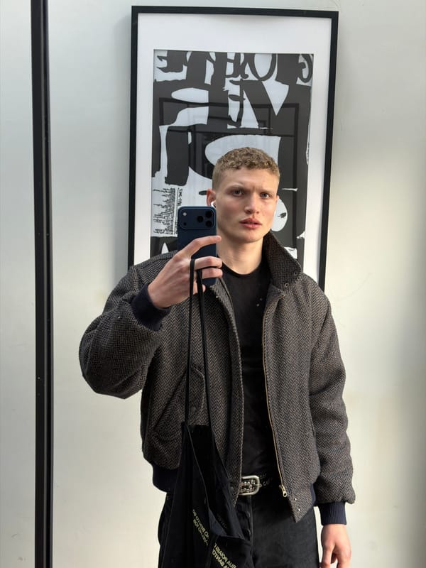 Person takes mirror selfie in herringbone jacket, London