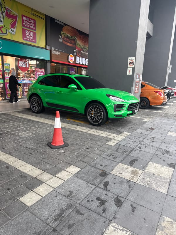 Green Porsche blocks pedestrian walkway near Kuala Lumpur shops