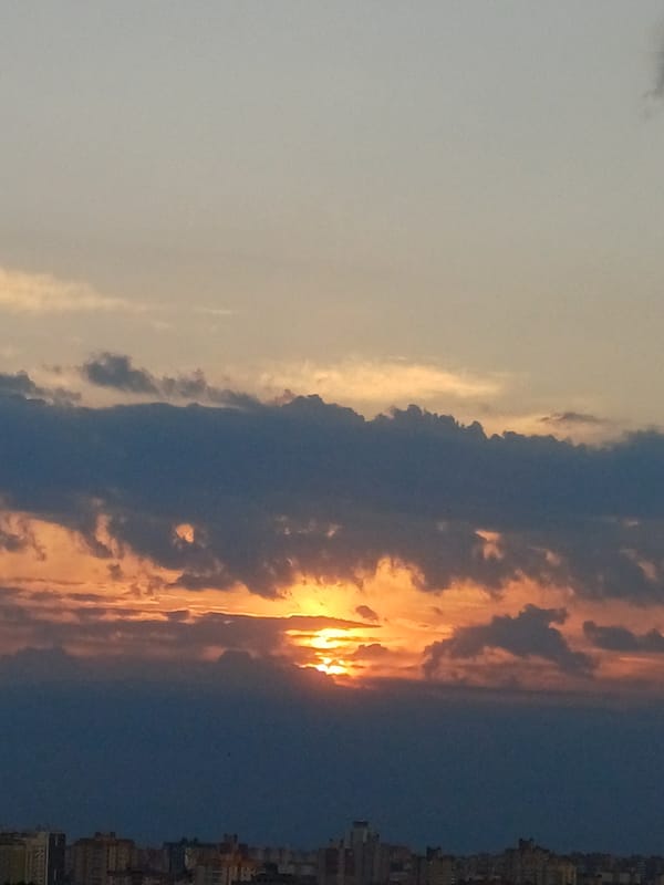 Urban sunset displays sectioned sky with contrasting cloud formations