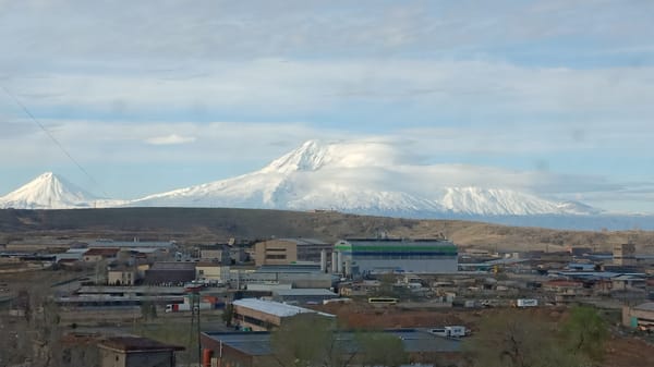 Snow-capped mountains backdrop viewed from Yerevan under cloudy skies