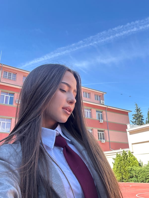 Woman in school uniform poses near reflective surface outdoors