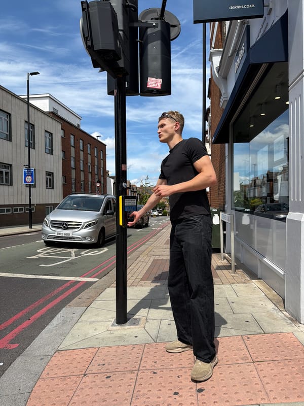 Pressing a pedestrian crossing button on a sunny London street