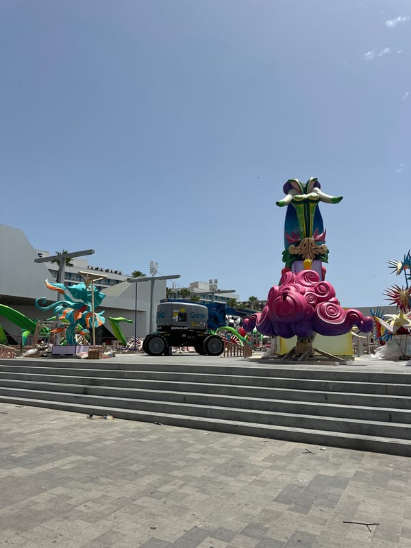 Busy Mediterranean promenade with beach crowds, palms, and street art