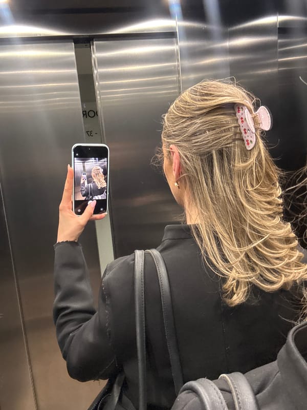 Mirror selfie in a London elevator, cherry claw clip in frame
