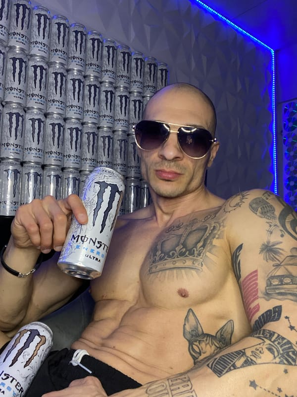 Man poses with Monster Energy cans in LED-lit room