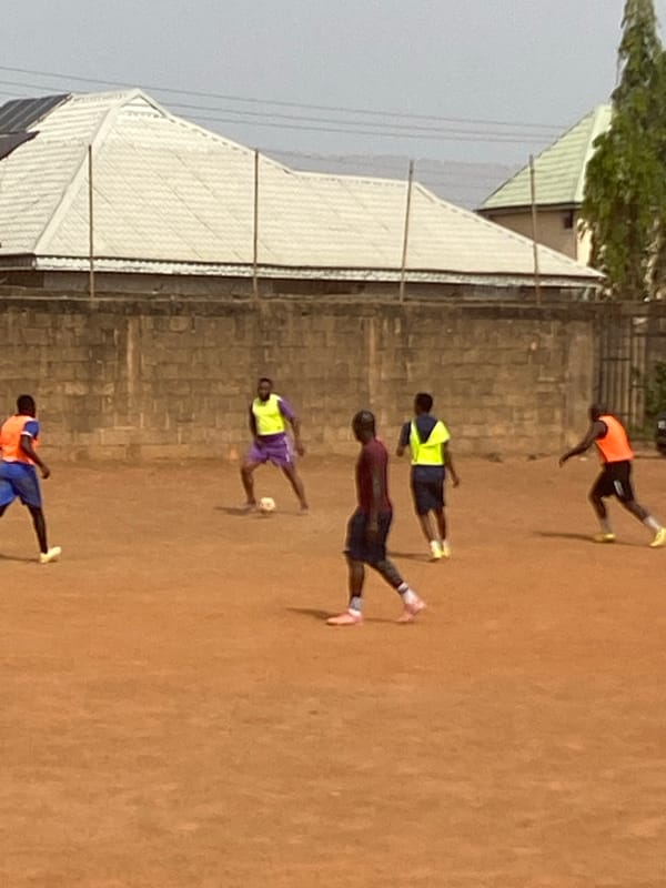 Five people gather on dirt field in Jos, Nigeria