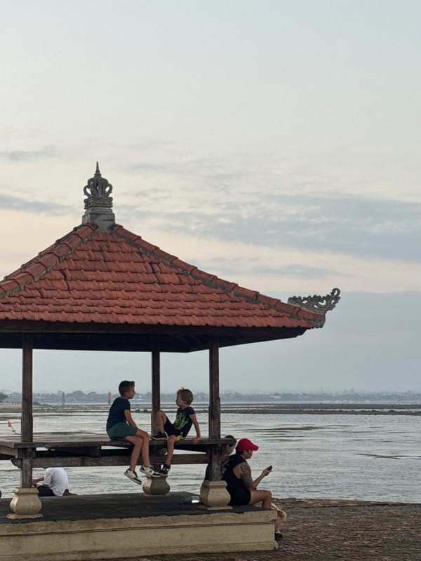 Conversation inside a carved Balinese pavilion in Denpasar