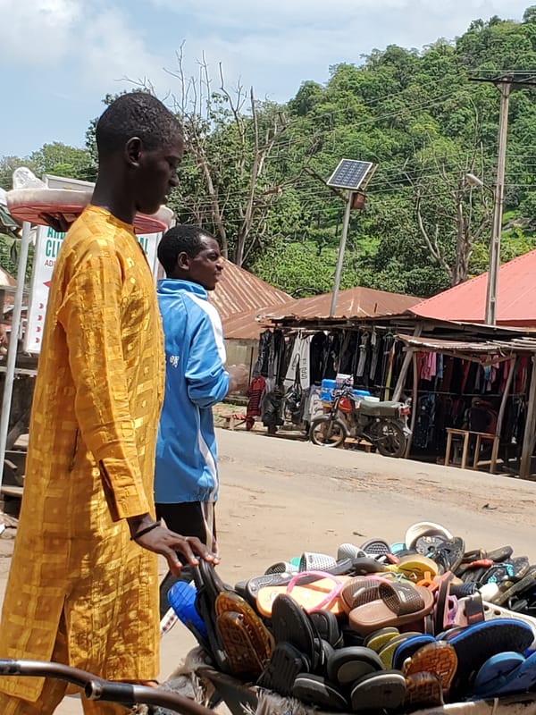 Two men browse sandals at street vendor in Mararaba