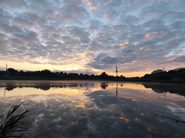 Sunrise clouds reflecting over a still lake in Khroly, Ukraine