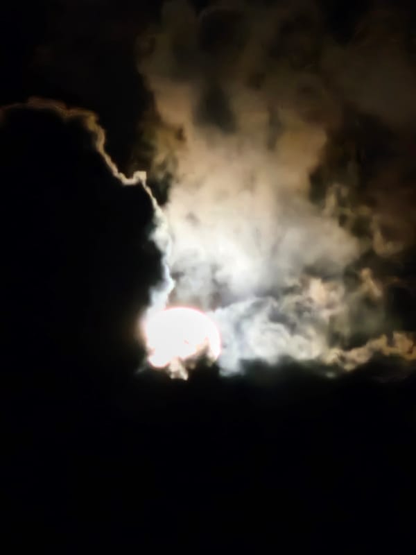 Full moon night over Denpasar streets and cloudy skies