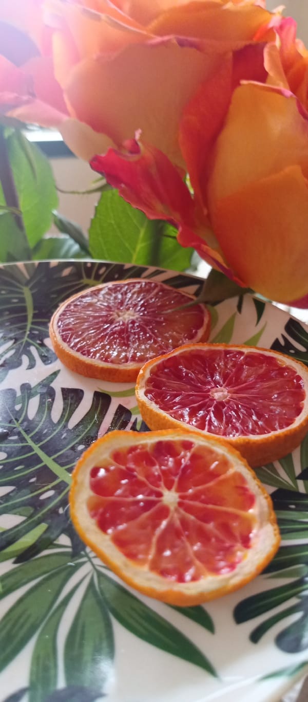 Dried blood orange slices arranged with rose on decorative plate