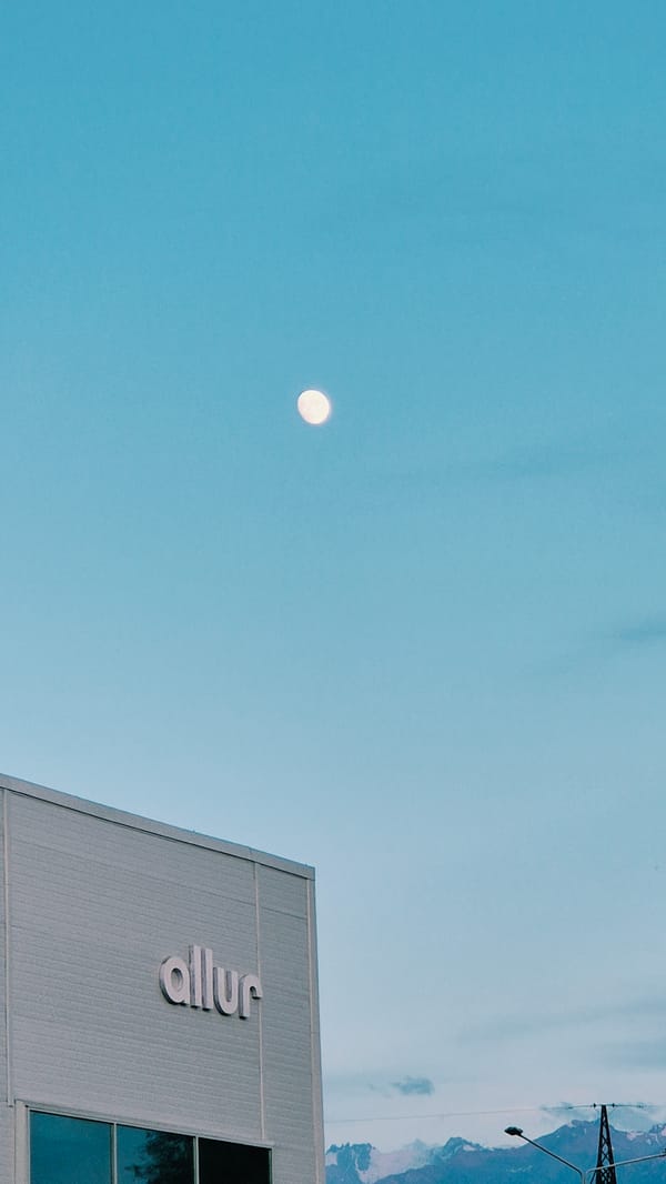 Moon over a city building, then a plane crossing a sunset sky