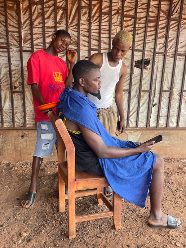 Three young men gather outdoors in Ogbe, Nigeria