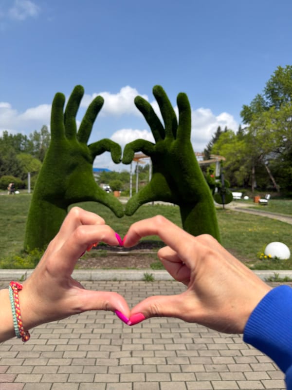 Woman photographs topiary hand sculptures in Birobidzhan park
