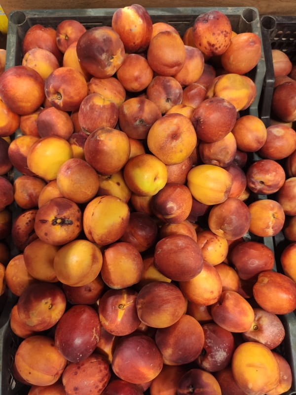 Fresh fruit, soda shelves, and produce browsing at a Tashkent market