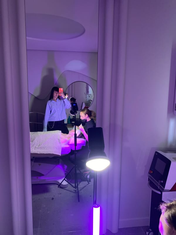 Woman takes mirror selfie in purple-lit indoor studio space