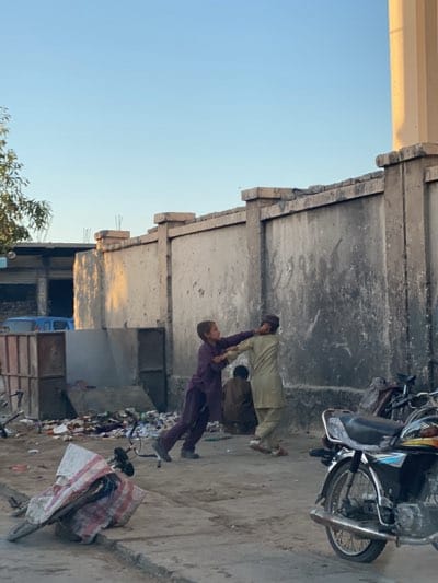 Boys fight, person pulls cart in Kandahar streets