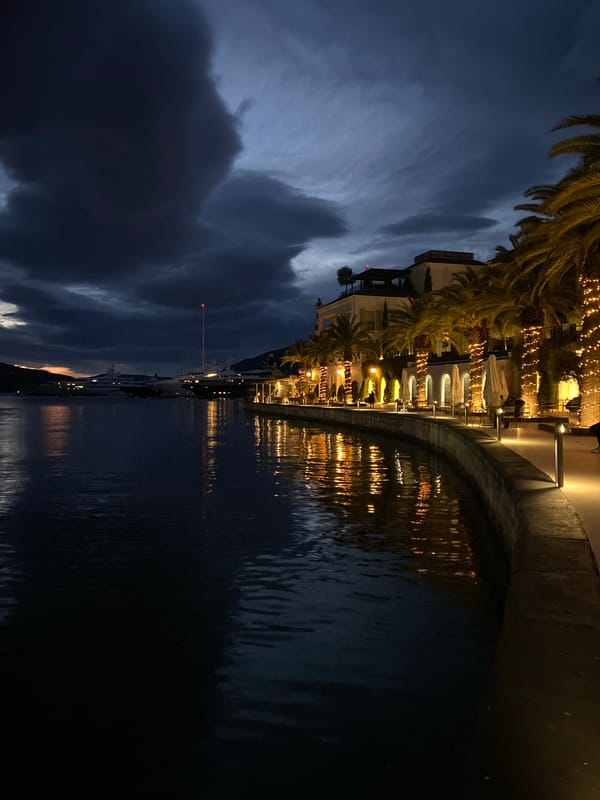 Couple documents evening stroll through illuminated Porto Montenegro marina district