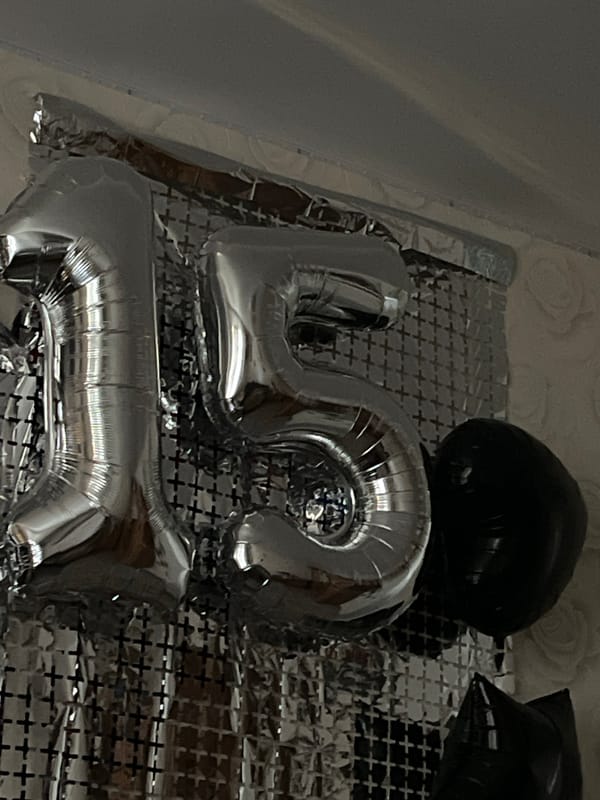 Silver '15' foil balloons against a crinkled metallic backdrop
