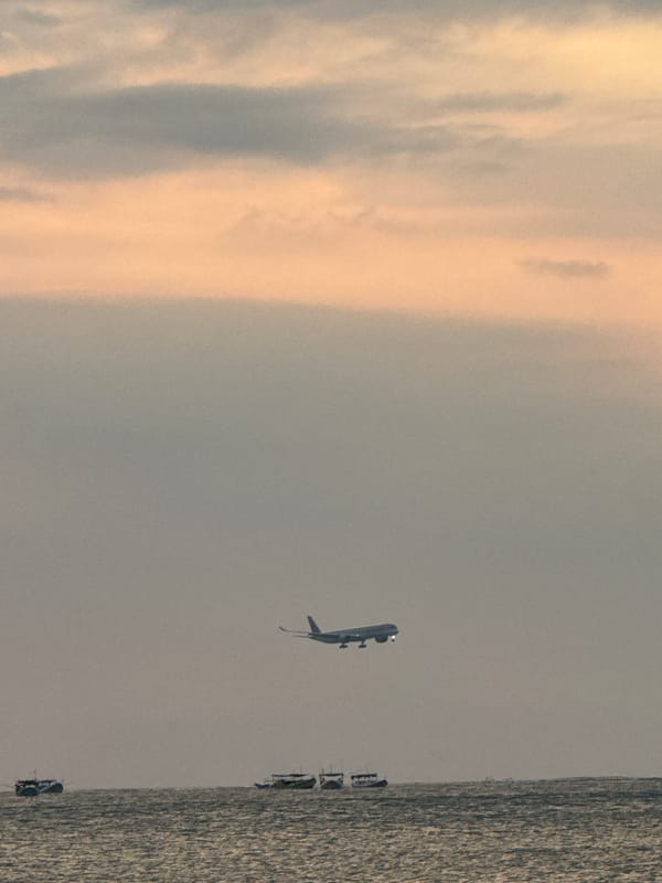 Plane on approach over Kuta's coast at sunset