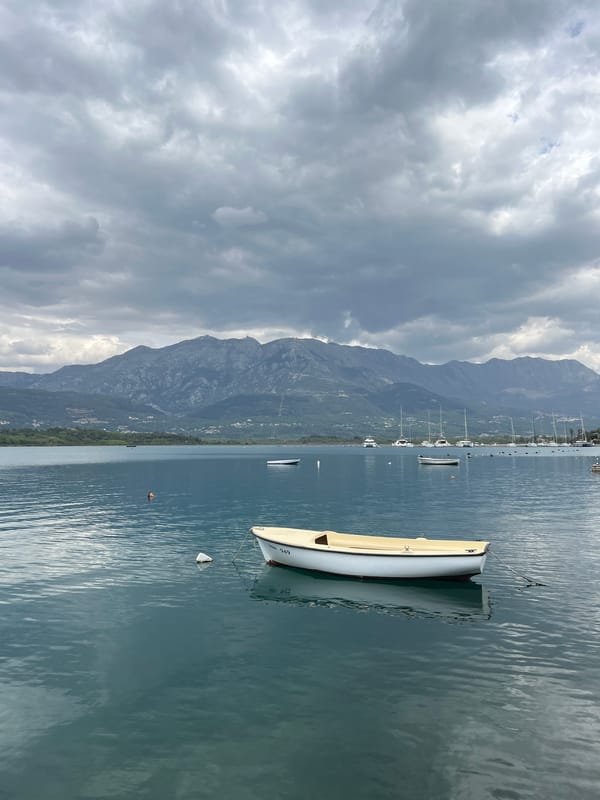 Lone sailor navigates Bay of Kotor under overcast skies