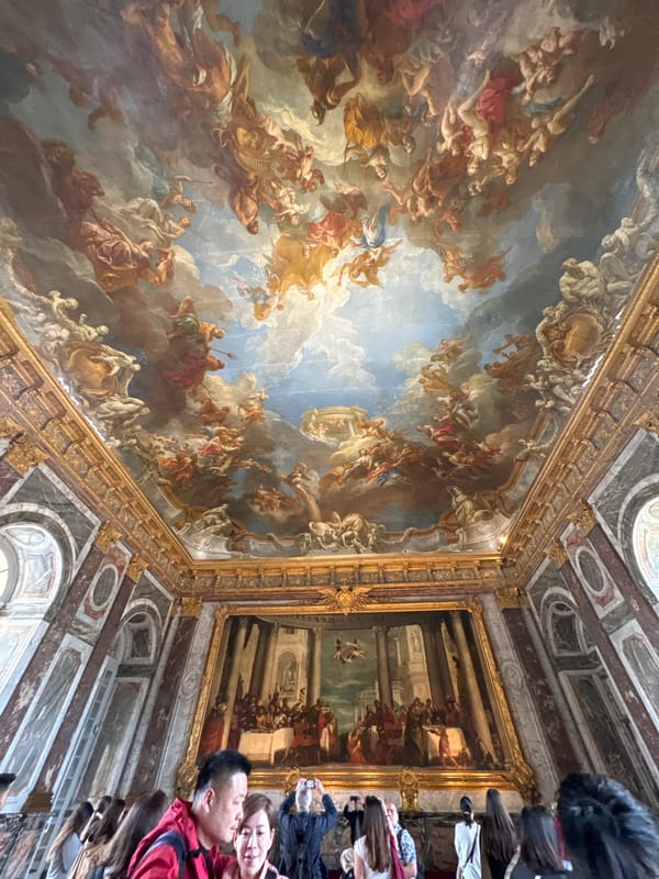 Tourist documents ornate ceiling art at Palace of Versailles