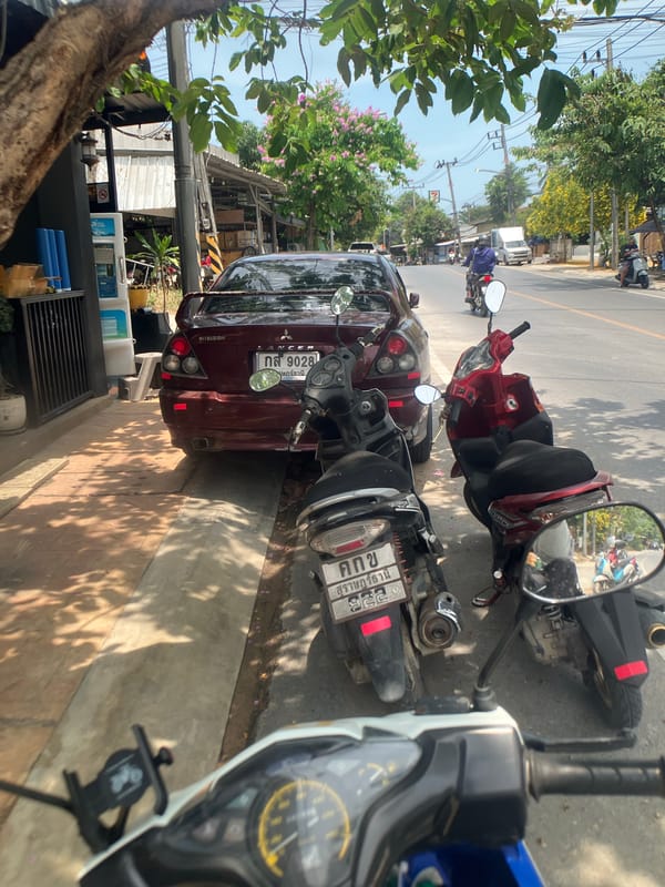 Vehicles parked on street in Baan Plai Laem, Thailand