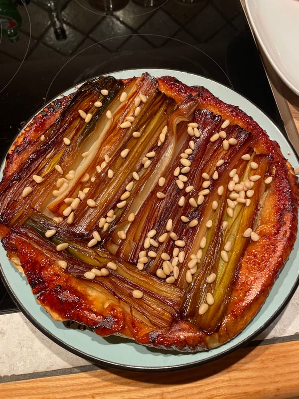 Caramelized leek tart with pine nuts spotted on plate