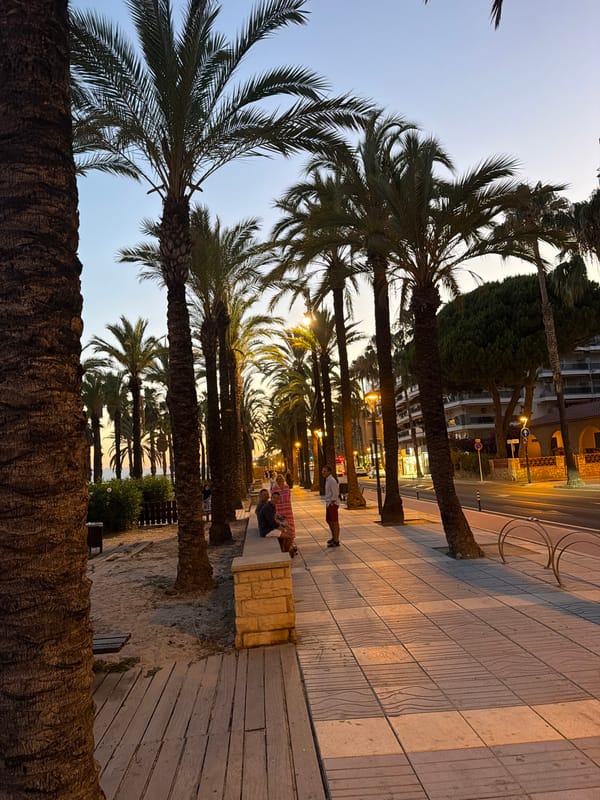 Salou waterfront promenade at dusk, green-lit bar in view