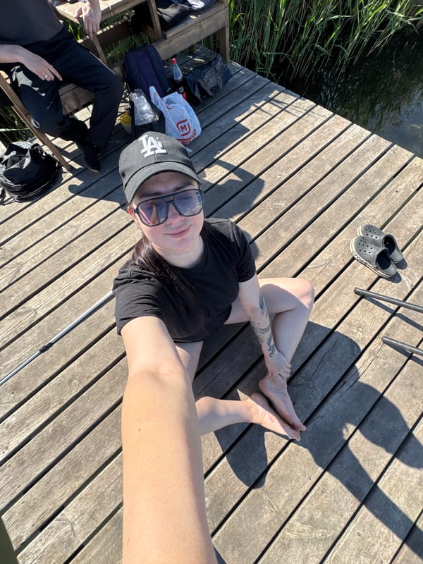 Person in LA cap enjoys leisurely fishing session on wooden dock