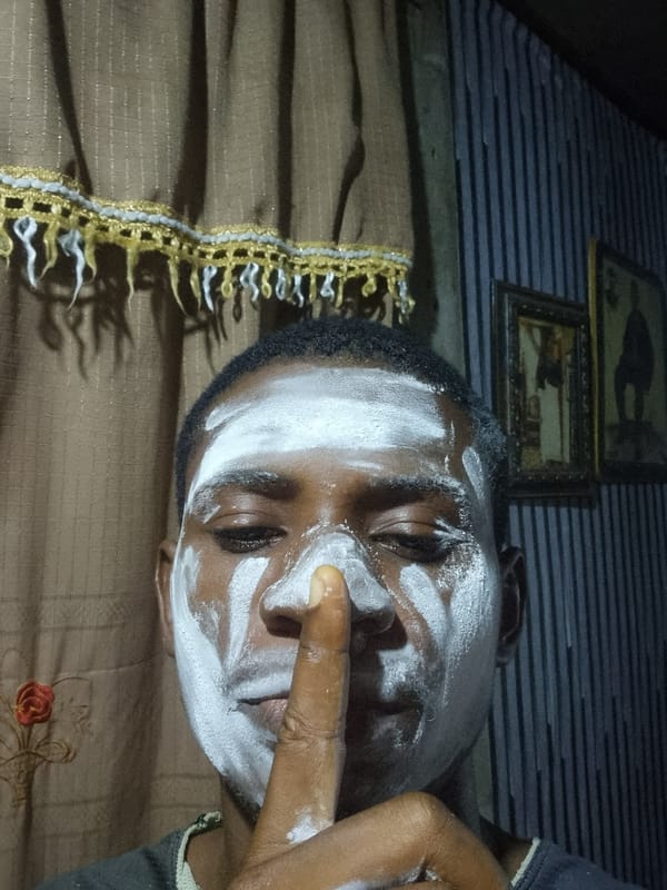 Man applies white face paint in Onitsha home setting
