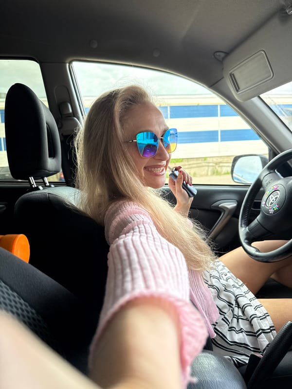 Woman in pink sweater sits in car in Chaikovsky