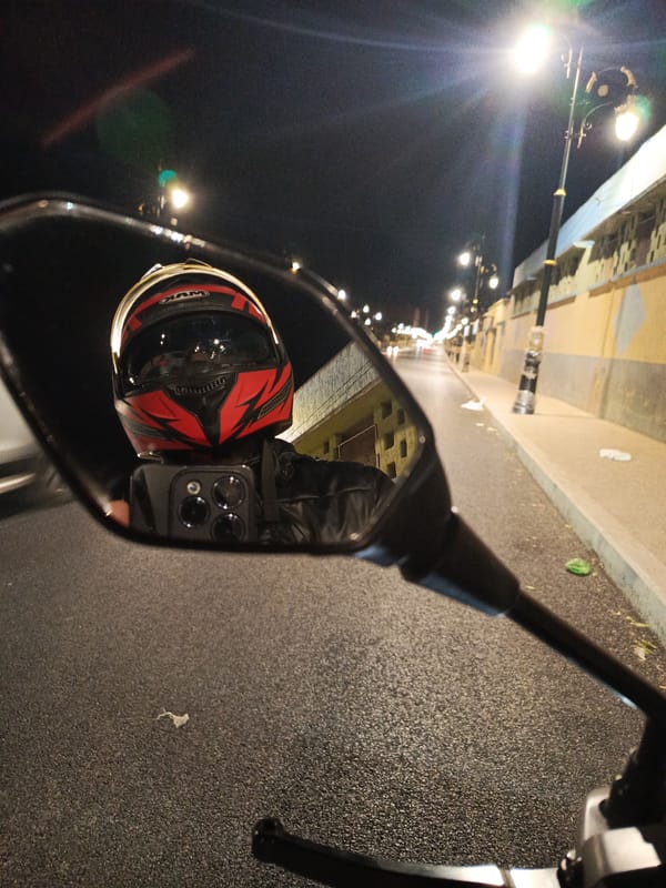 Motorcyclist captured in side mirror reflection while riding in Meknes