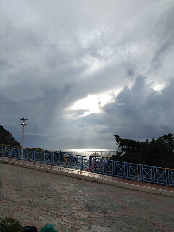 Morning sunlight breaks through clouds over walkway in Zia, Greece