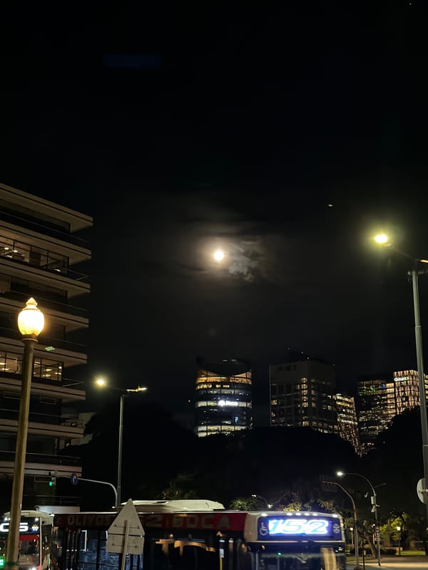 Full moon visible through clouds over Buenos Aires nightscape