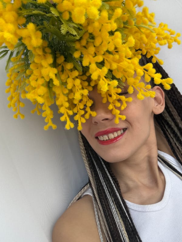 Person poses with yellow mimosa flowers in portrait session