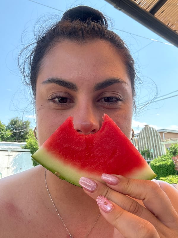 Watermelon slice held up to the face, camera-facing.