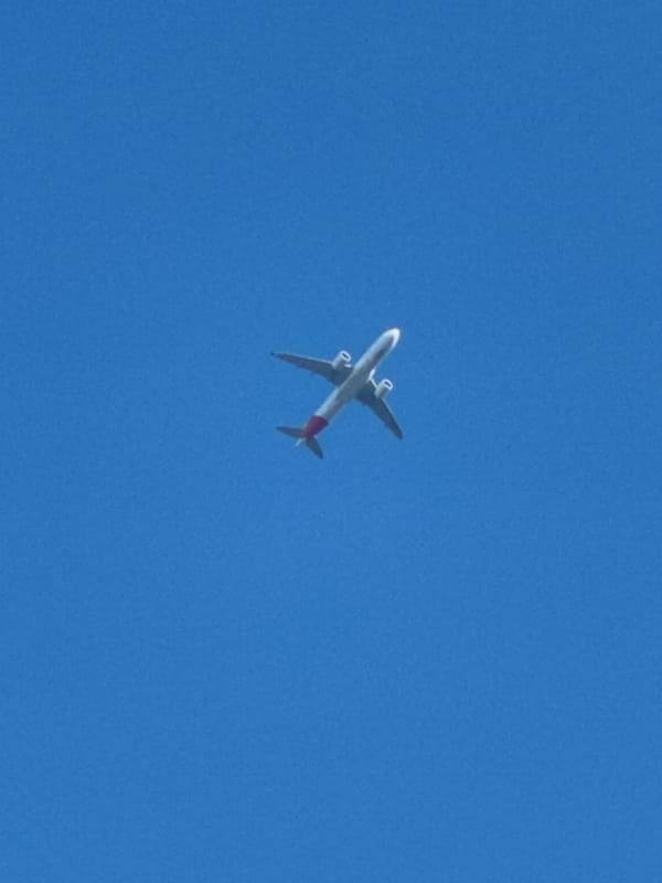 Red-tailed passenger jet crosses clear skies over southeast London