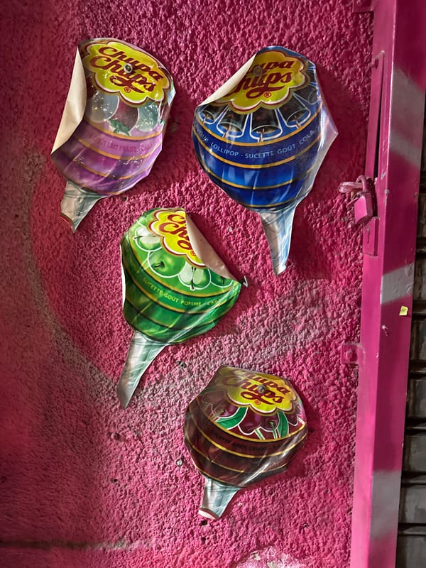 Colorful Chupa Chups wrappers stuck on pink wall