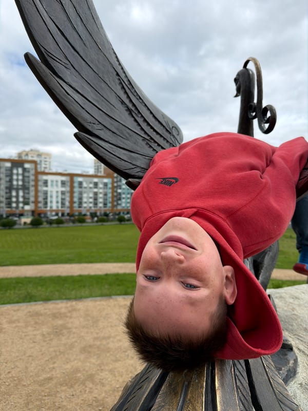 Climbing on a bronze phoenix sculpture in an urban park