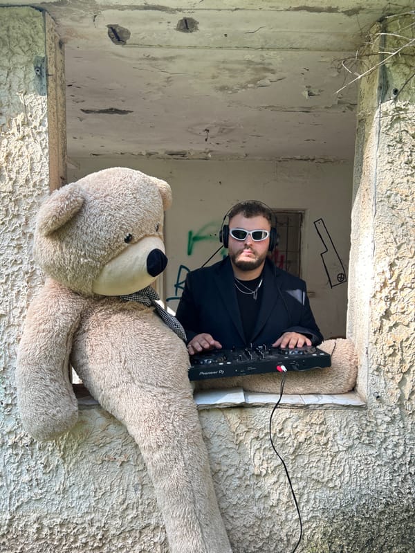 Man poses with teddy bear in abandoned building window